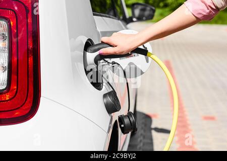 Nahaufnahme Womans Hand hält ein Ladegerät Stecker des Elektroautos. Emissionsfreies Fahrzeug Stockfoto