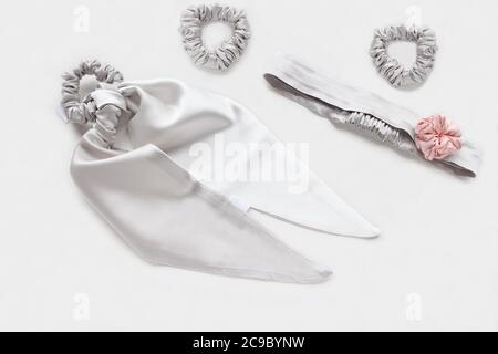 Slver oder graue Haaraccessoires mit Textil-Rose. Seide Scrunchy isoliert auf weißem Hintergrund. Flat Lay Friseur Werkzeuge und Zubehör für Frau - Stockfoto