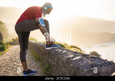 Fit Tattoo Mann binden seine Sportschuhe im Freien während Jogging-Session - Workout und Fitness Lifestyle Konzept - Fokus auf Hände Stockfoto