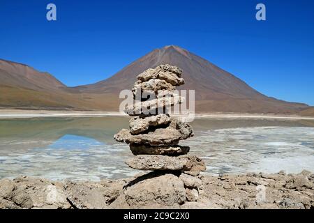 Steinstapel von Reisenden an der Küste der Laguna Verde oder dem Grünen See mit Vulkan Lincancabur im Hintergrund, Bolivien Stockfoto