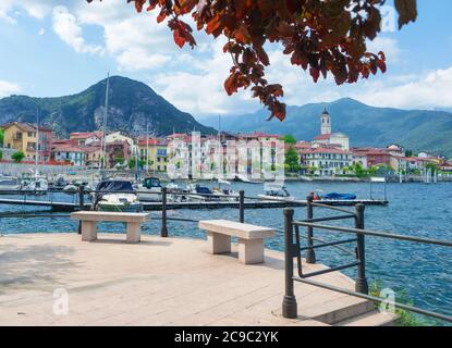 Schönes Panorama von einer Terrasse mit Blick auf den Lago Maggiore. Malerisches Dorf umgeben von Bergen mit einem Yachthafen.Italien Stockfoto