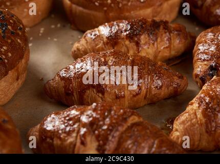 Gebackene Croissants in einem Backblech auf braunem Pergamentpapier, leckeres und appetitliches Gebäck Stockfoto