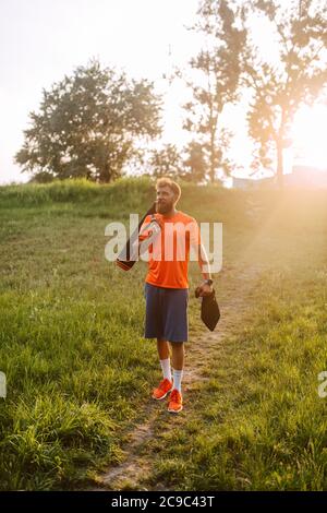 Ein sportlicher Fitness-Kaukasianer in einem orangefarbenen T-Shirt geht zum Training im Wald. Outdoor-Sport Stockfoto