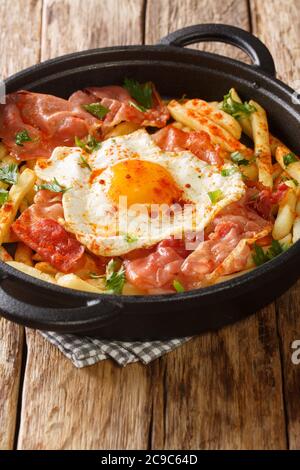 Spanische Küche Spiegelei mit Pommes Frites und Schinken Nahaufnahme in einem Teller auf dem Tisch. Vertikal Stockfoto