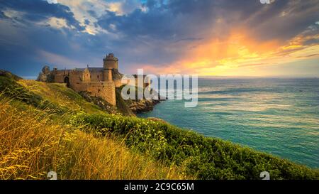 Romantischer Sonnenuntergang in Fort-La-Latte, einer der berühmtesten Burgen der Bretagne. Es handelt sich um eine Festung aus dem 14. Jahrhundert, die auf einer Klippe in der Baie de la Fresnaye erbaut wurde. Stockfoto