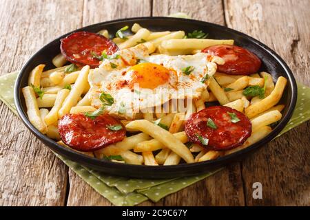 Leckeres Essen Spiegelei mit Pommes frites und Chorizo Nahaufnahme in einem Teller auf dem Tisch. Horizontal Stockfoto