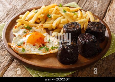 Huevos Rotos mit Bratkartoffeln und Blutwurst in der Nähe auf einem Teller auf dem Tisch. Horizontal Stockfoto