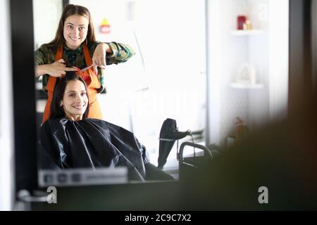 Friseur und Kunde schauen in Spiegel und lachen Stockfoto