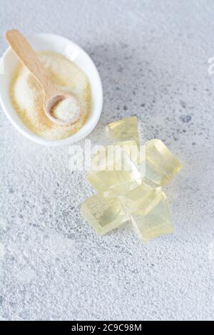 Gelatine, Agar-Agar, gallertartige Masse (Würfel in Form von Kristallen) auf grauem Grund. Geliermittel (Kollagen) für kulinarische Süßwaren Stockfoto