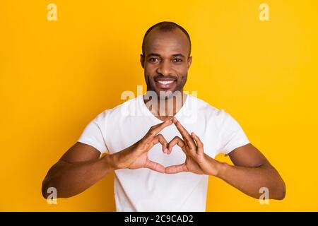 Foto von attraktiven dunklen Haut Kerl halten Arme machen Herz Form romantisch Stimmung Ausdruck Gefühle Freundin tragen lässige weiße T-Shirt Isoliert hell Stockfoto