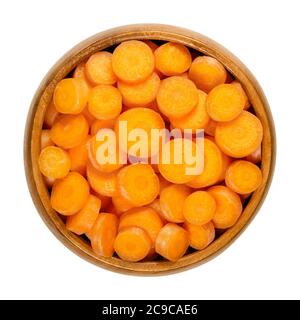 Kleine Karottenscheiben in Holzschüssel. Knusprig und frisch, ungeschälte, kleine und junge Karotten, in runde Scheiben geschnitten, verzehrfertig und als Snack. Nahaufnahme Stockfoto