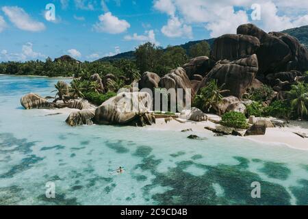 Insel 'La digue' auf den Seychellen. Silberner Strand mit Granitstein und Dschungel. Mann, der Urlaub am Strand genießt und Spaß mit dem Kajak hat. Antenne V Stockfoto