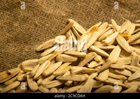 Weiße Sonnenblumenkerne gebraten mit Meersalz in der Masse auf einem Hintergrund von grob-strukturierten Quappen. Nahaufnahme Stockfoto