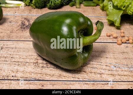 Grüne gesunde Paprika auf einem braunen Holzhintergrund. Produkte für die Keto-Diät, glutenfreie Ernährung und richtige Ernährung für die Gewichtsabnahme. Stockfoto