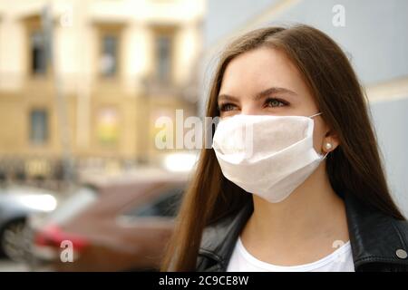 Junge Frau mit medizinischer Gesichtsmaske auf der Straße. Stockfoto