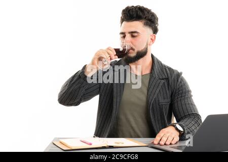 Ein hübscher Geschäftsmann, der im Anzug gekleidet ist und Rotwein trinkt, sitzt Stockfoto