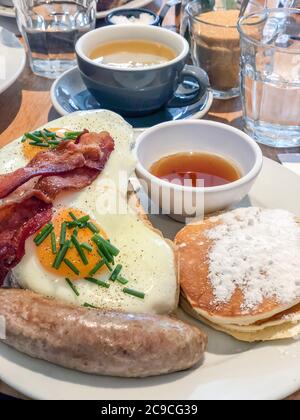 Frühstück mit Ei, Pfannkuchen und Wurst auf dem Tisch in einem Café Stockfoto