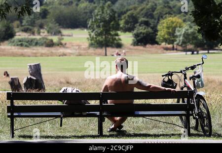 Ein Radfahrer entspannt sich auf einer Bank im Regent's Park, London. Stockfoto