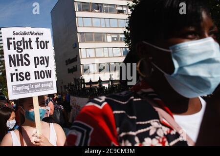 Während des Protestes vor dem St. Thomas' Hospital in London werden Mitarbeiter des National Health Service (NHS), die eine Gesichtsmask tragen, ein Plakat halten, auf dem sie Menschen bitten, für eine Erhöhung der NHS-Gehälter zu kämpfen.rund 900,000 Beschäftigte des öffentlichen Sektors in ganz Großbritannien werden dieses Jahr als Dankesgeste eine überhöhliche Gehaltserhöhung erhalten Aus dem Finanzministerium für ihre Bemühungen während der Coronavirus-Pandemie. Die Gehaltserhöhung ist jedoch ausschließlich für Krankenschwestern und andere Mitarbeiter vor der Haustür aufgrund eines dreijährigen Lohnverhandlungs, den sie 2018 ausgehandelt haben, was sie dazu führte, aus Protest auf die Parliament Street in Richtung Downing Street in London zu marschieren. Stockfoto