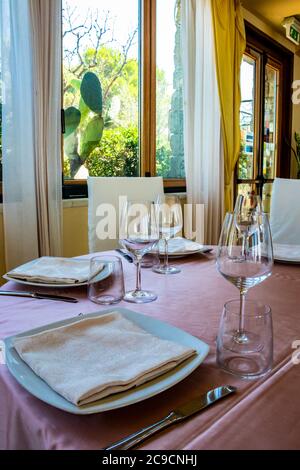 Tischset für eine Zeremonie in einem italienischen Restaurant. Feiern für eine Hochzeit. Korb mit Champagner. Blumenschmuck. Rosa Tischdecke. Luxus, Ele Stockfoto