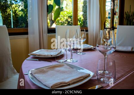 Tischset für eine Zeremonie in einem italienischen Restaurant. Feiern für eine Hochzeit. Korb mit Champagner. Blumenschmuck. Rosa Tischdecke. Luxus, Ele Stockfoto