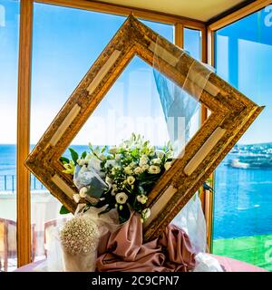 Blumenschmuck für die Hochzeit, in einem italienischen Restaurant, bestehend aus einem großen Holzrahmen. Der schöne Blick auf das Meer aus dem großen Fenster. Stockfoto