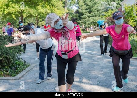 Eine Gruppe von chinesisch-amerikanischen Frauen, die Masken tragen und Distanzen beobachten, üben modernen chinesischen Tanz. Bei einem Outdoor-Kurs in Flushing, Queens, NYC Stockfoto