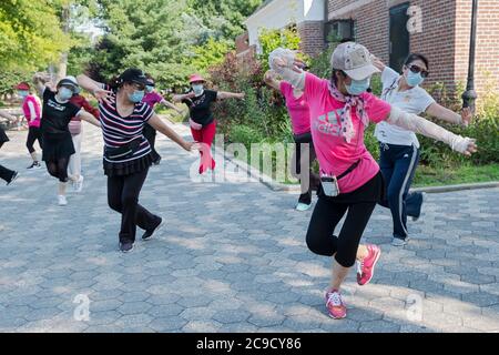 Eine Gruppe von chinesisch-amerikanischen Frauen, die Masken tragen und Distanzen beobachten, üben modernen chinesischen Tanz. Bei einem Outdoor-Kurs in Flushing, Queens, NYC Stockfoto