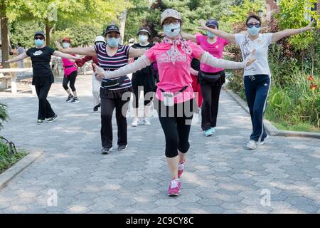 Eine Gruppe von chinesisch-amerikanischen Frauen, die Masken tragen und Distanzen beobachten, üben modernen chinesischen Tanz. Bei einem Outdoor-Kurs in Flushing, Queens, NYC Stockfoto