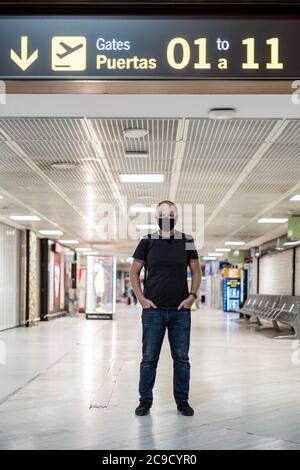 Mann mit Schutzmaske vor Abflug am leeren Flughafen Stockfoto