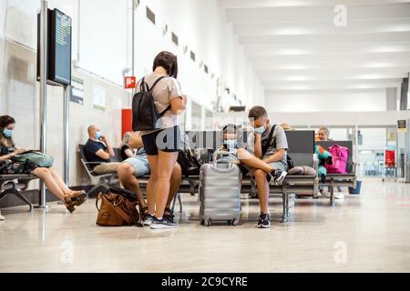Sevilla, Spanien - 4. Juli 2020: Maskierte Familie wartet auf die Abfahrt am Flughafen Stockfoto