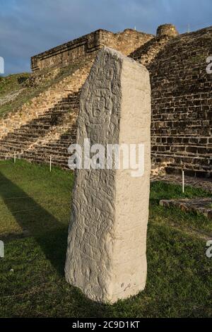 Stela 9 ist ein Steinobelisk, der an allen vier Seiten vor der Nordplattform der präkolumbianischen Zapoteken-Ruinen des Monte Alban in Oaxaca, Mexiko, geschnitzt wurde Stockfoto