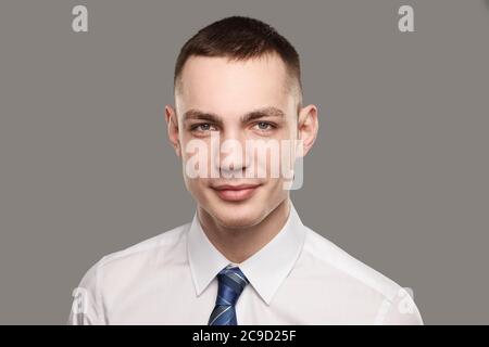 Gutaussehende zuversichtlich jungen kaukasischen Mann in weißem Hemd und Krawatte stehen über grauen Hintergrund. Stockfoto