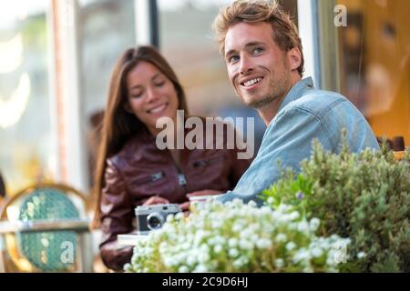 Junger Stadtmensch genießt es, mit einem Freund in der Stadt am Restauranttisch zu sitzen. Europäischer Urlaub für Paare. Lockerer Lebensstil. Stockfoto