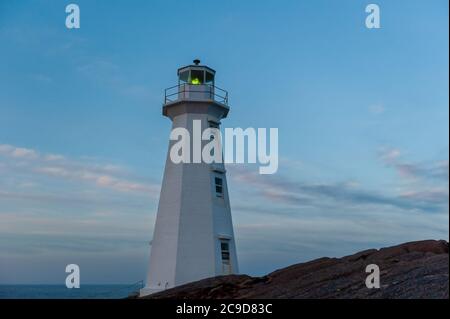 Ein an Land gebauter Leuchtturm auf einem felsigen Fundament mit Stufen und einem Handlauf, der zur Struktur führt. Stockfoto