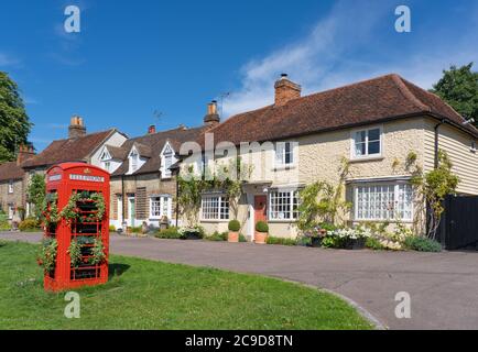 Traditionelle englische Dorfszene mit alten Häusern und einer alten Telefonbox, die im Vordergrund mit Blumen geschmückt ist. Standon, Hertfordshire. VEREINIGTES KÖNIGREICH Stockfoto