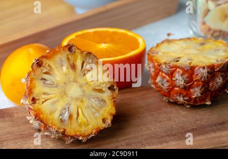 Halbierte Ananas und Orange auf Holzbrett Stockfoto