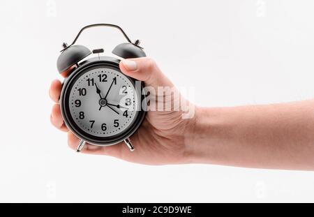 Hand mit schwarzem Wecker auf weißem Hintergrund Stockfoto