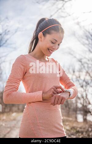 Frau Vorbereitung Fitness Smart Uhr zum Laufen. Sportlerin, die sich bereit für den Morgen in kalten frischen Luft draußen Natur Kontrolle Uhr Gerät laufen Stockfoto