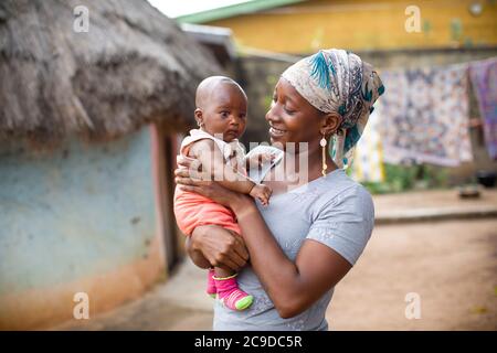 Junge Mutter zeigt Zuneigung zu ihrem neugeborenen Baby in Kouroussa, Guinea, Westafrika. Stockfoto