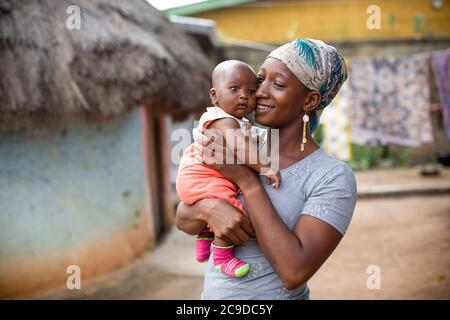 Junge Mutter zeigt Zuneigung zu ihrem neugeborenen Baby in Kouroussa, Guinea, Westafrika. Stockfoto