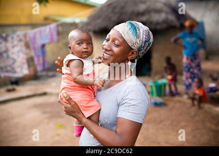 Junge Mutter zeigt Zuneigung zu ihrem neugeborenen Baby in Kouroussa, Guinea, Westafrika. Stockfoto