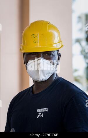 Bauarbeiter mit gelben Schutzmützen und Gesichtsmasken arbeiten an der Renovierung eines Hotels in Costa Adeje nach dem Covid 19 l Stockfoto