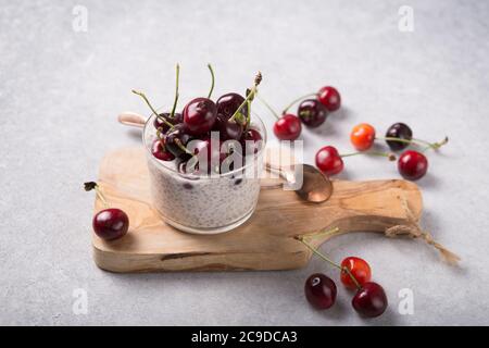 Chia Pudding mit Kirschbeeren, Naturjoghurt, in einem Glas auf einer grauen Oberfläche. Selektiver Fokus. Gesunde Nachtisch, richtige Ernährung, super Essen. Stockfoto