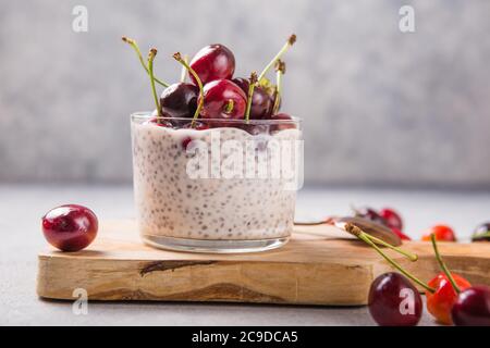 Chia Pudding mit Kirschbeeren, Naturjoghurt, in einem Glas auf einer grauen Oberfläche. Selektiver Fokus. Gesunde Nachtisch, richtige Ernährung, super Essen. Stockfoto