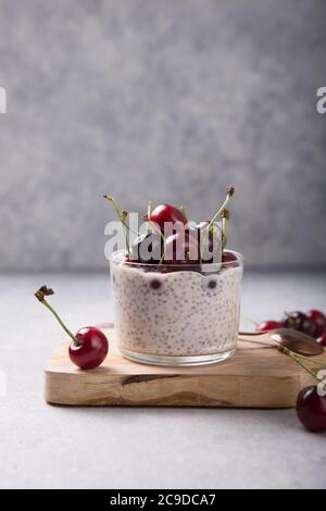 Chia Pudding mit Kirschbeeren, Naturjoghurt, in einem Glas auf einer grauen Oberfläche. Selektiver Fokus. Gesunde Nachtisch, richtige Ernährung, super Essen. Stockfoto