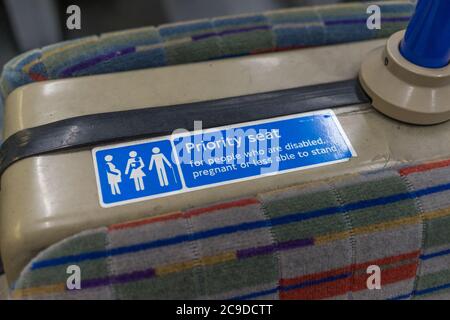 Schild mit dem Vorrangsitz für ältere oder behinderte Personen auf einem Zugsitz. London Stockfoto