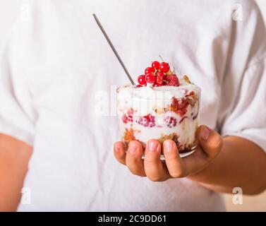 Lagenlook Dessert mit Biskuitkuchen, Schlagsahne und Himbeeren in Kinderhände Stockfoto