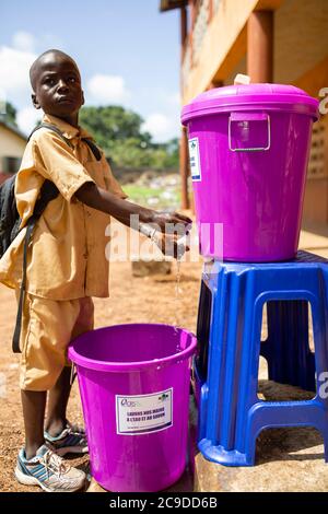 Ein Kind wäscht sich die Hände an einer Händewaschstation seiner Schule in Conakry, Guinea, Westafrika. Stockfoto