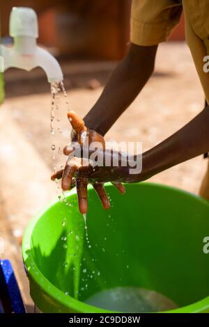 Ein Kind wäscht sich die Hände an einer Handwaschstation seiner Schule in Conakry, Guinea, Westafrika. Stockfoto